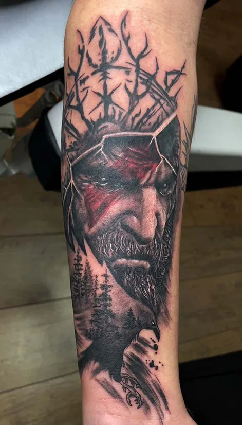 Black & Grey Tattoo am Unterarm: Wikinger mit roter Kriegsbemalung, Geweih- und Runenkrone, Rabe und Tannenwald