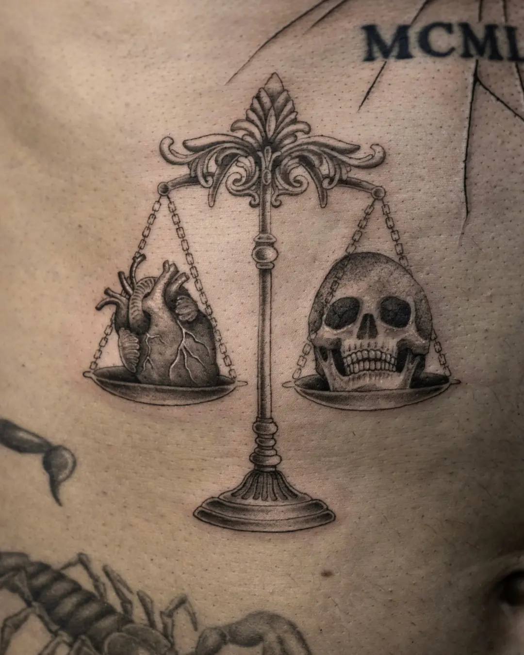 Fineline Tattoo einer verzierten Waage mit anatomischem Herz und Totenkopf in den Schalen am Bauch, Black & Grey, Wien