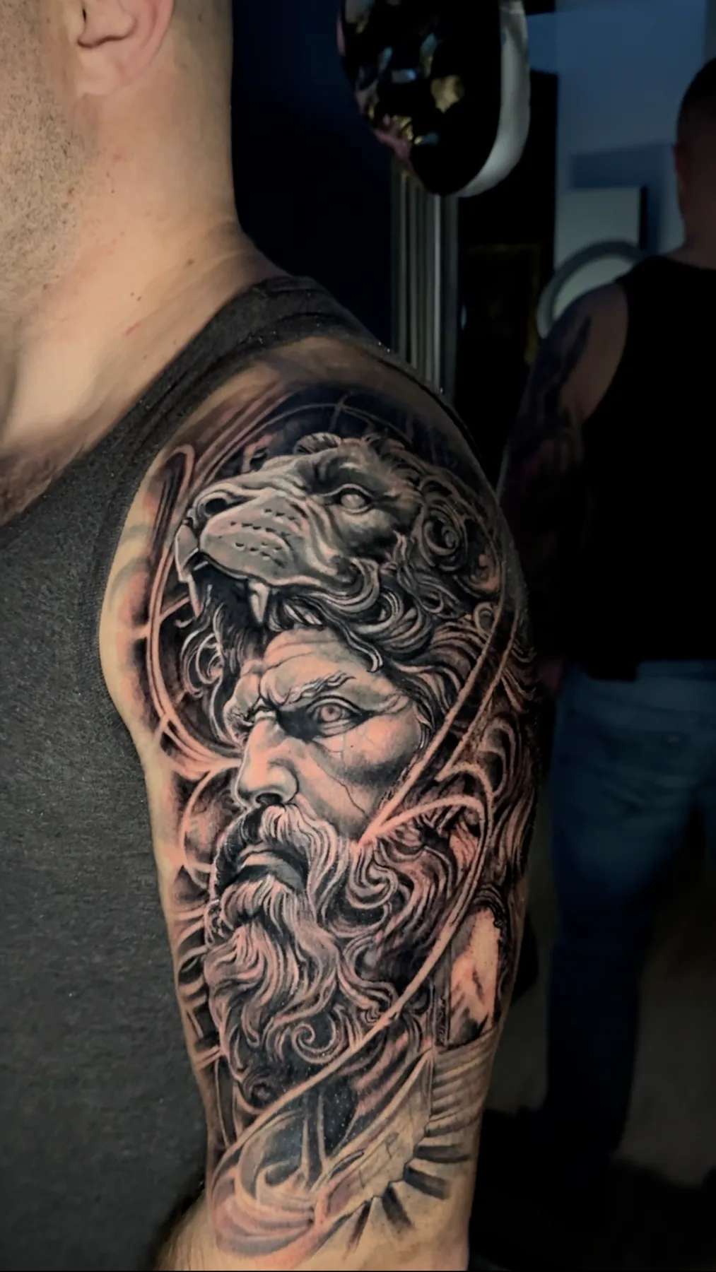 Realistisches Black & Grey Tattoo von Herkules mit dem Fell des Nemeischen Löwen über dem Kopf an Schulter und Oberarm, Wien