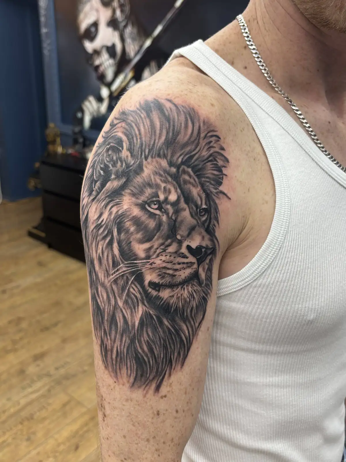 Realistisches Löwenkopf-Tattoo in Black & Grey mit voller Mähne an Schulter und Oberarm, fotografiert im Tattoo Studio Wien